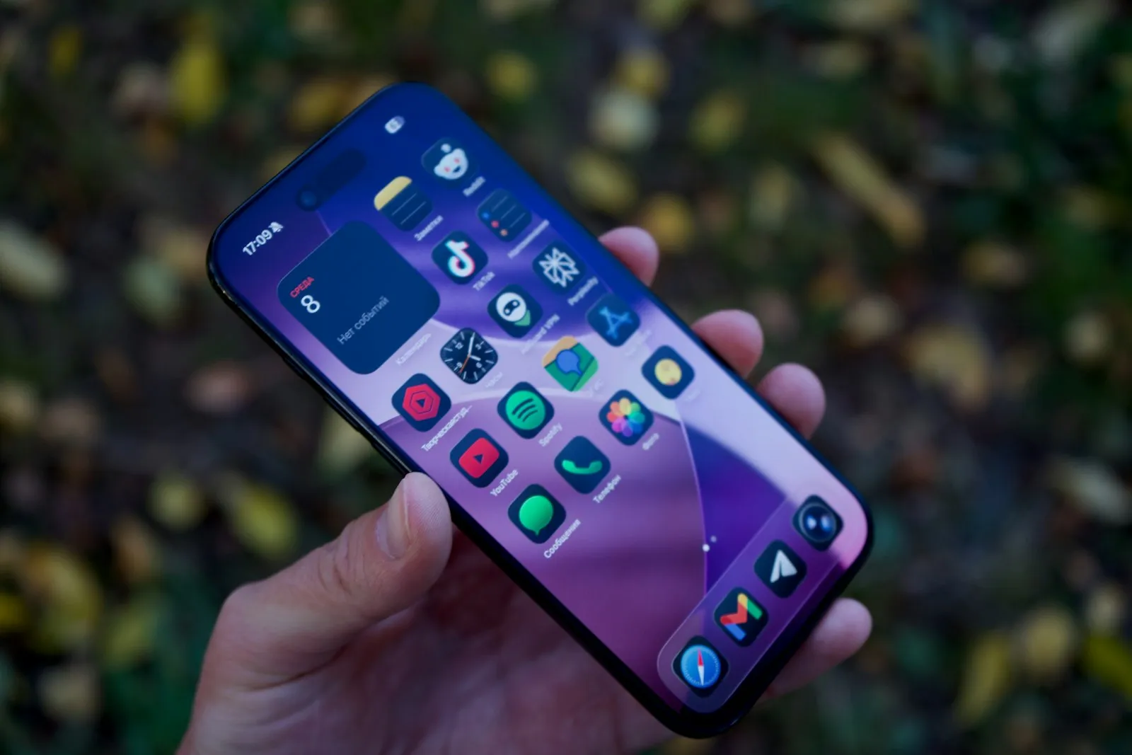 A hand holding a smartphone that displays a grid of colorful app icons
