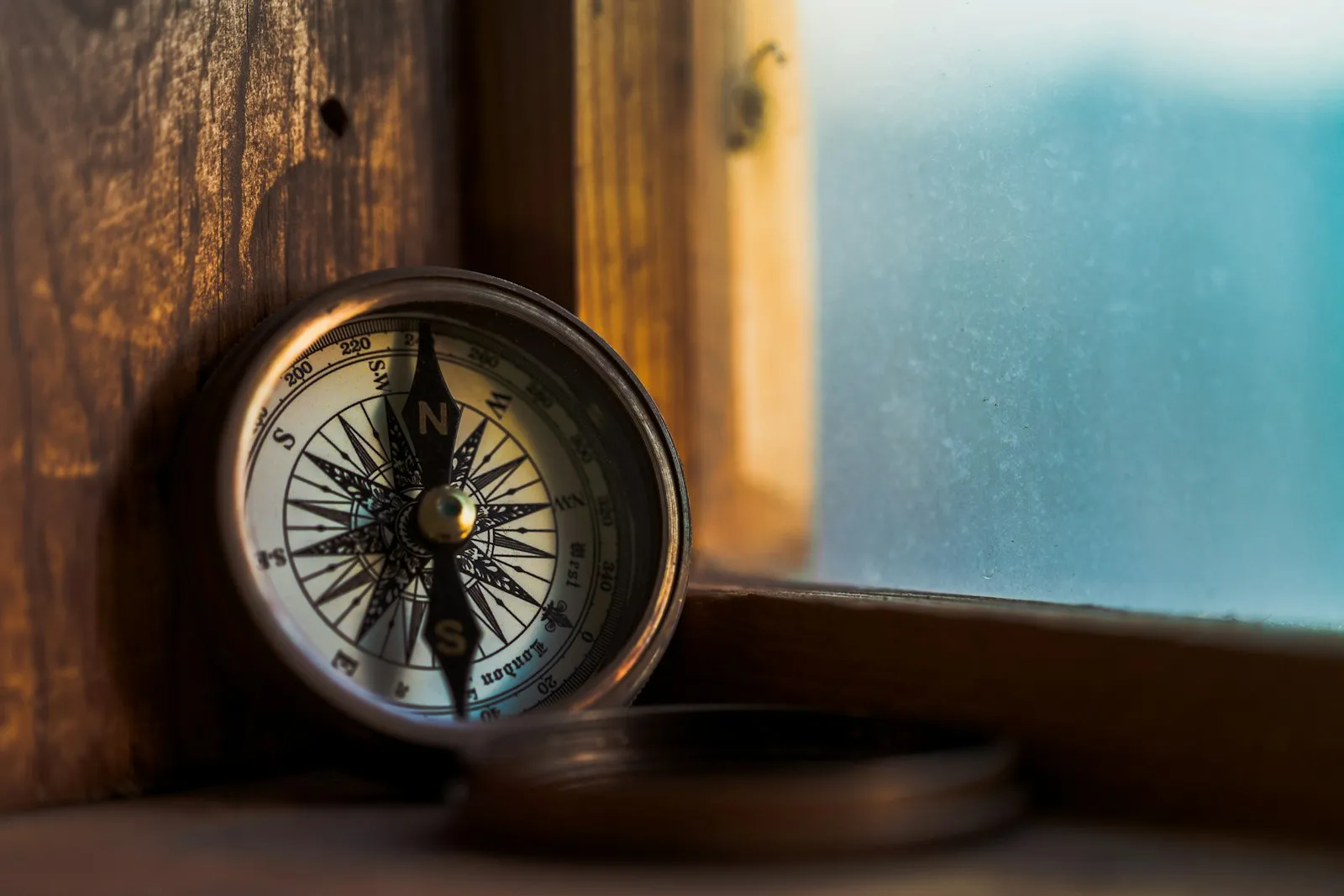 Brass compass resting on a wooden window ledge