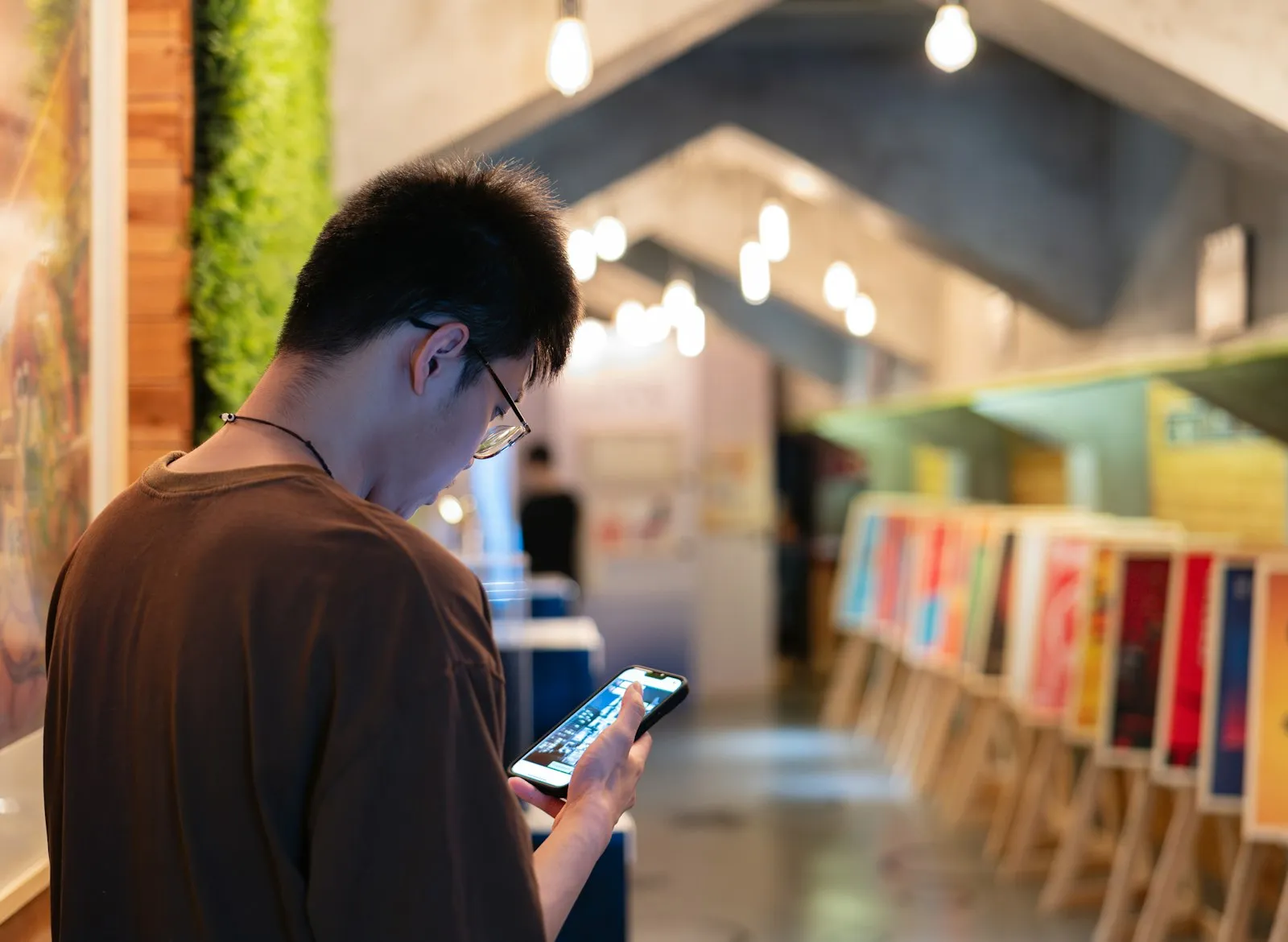 A man in glasses looks at a phone inside a shop