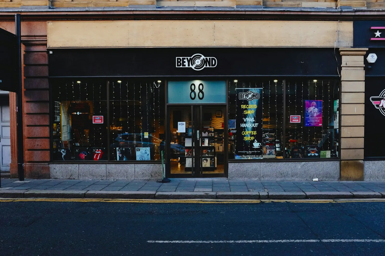Shopfront of a record shop with a lit window display on a city street