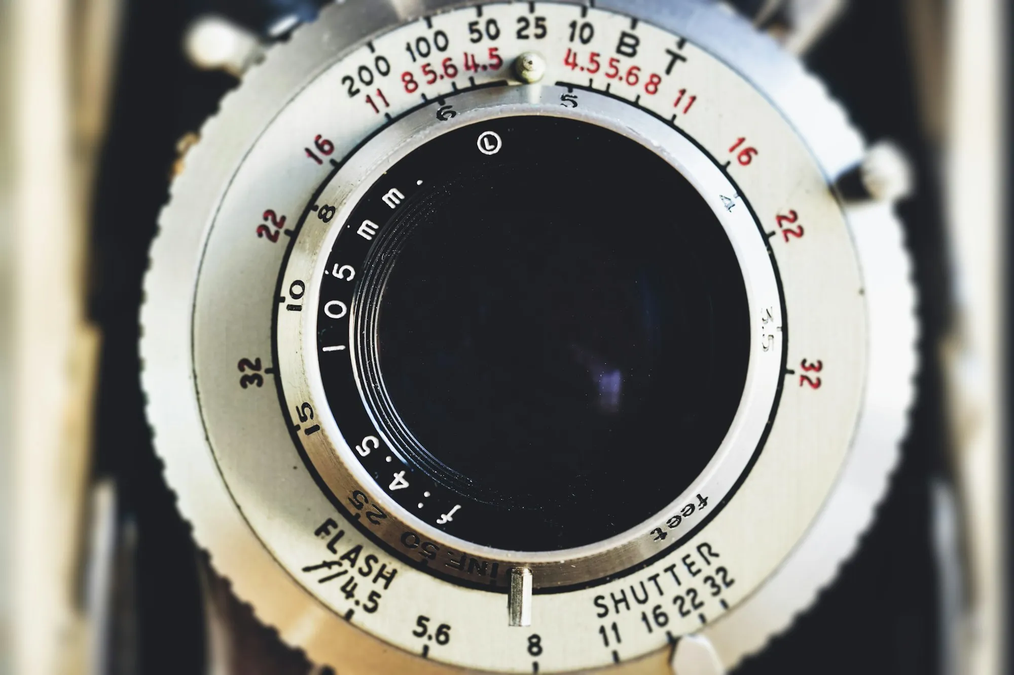 Close-up of a vintage camera lens ringed by aperture and shutter speed dials