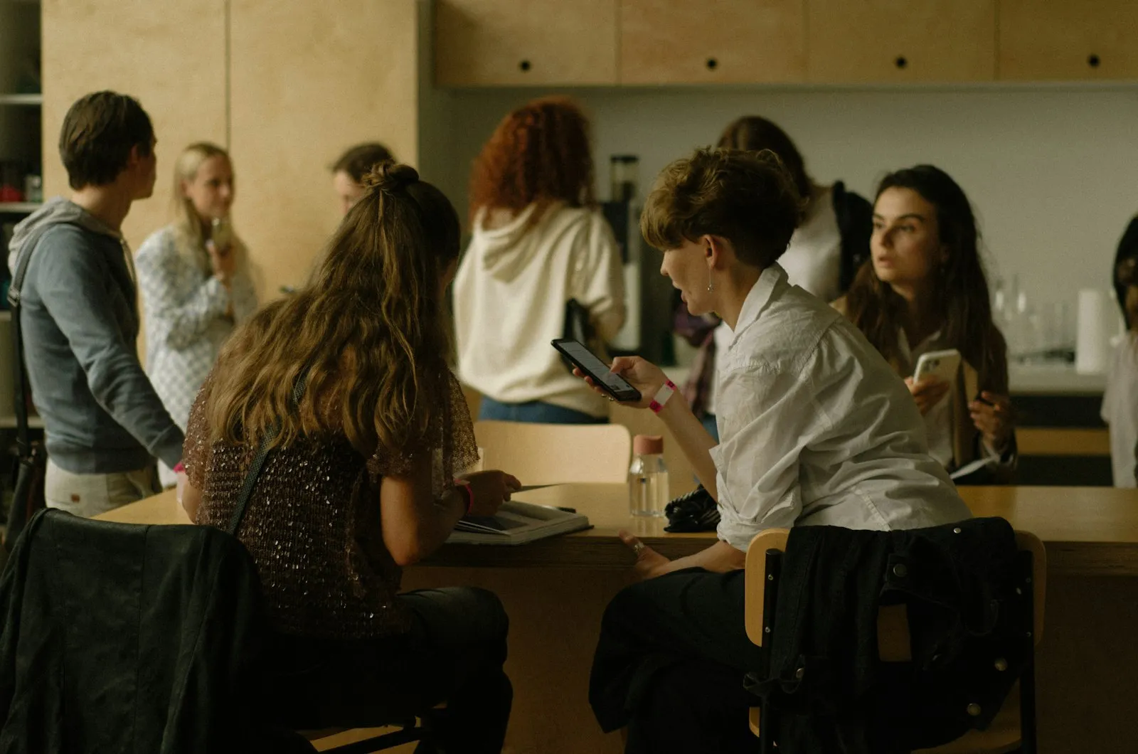 A group of people sitting around a table, each looking at a phone