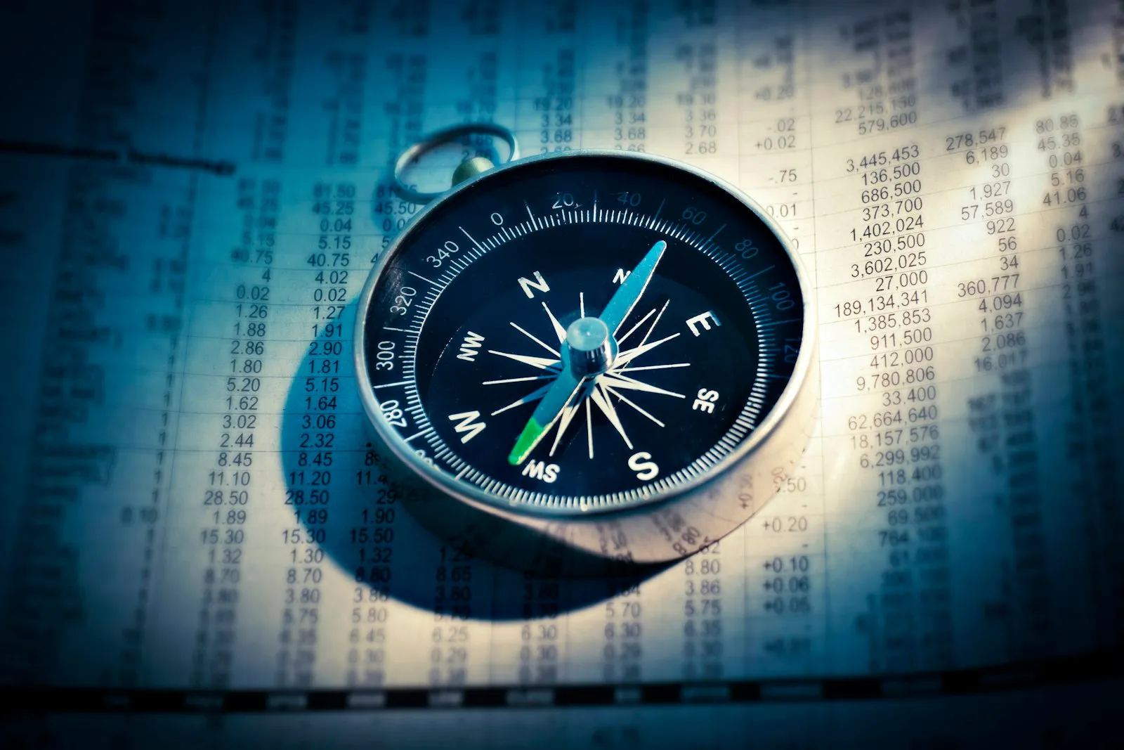 Silver compass resting on a printed page of financial figures