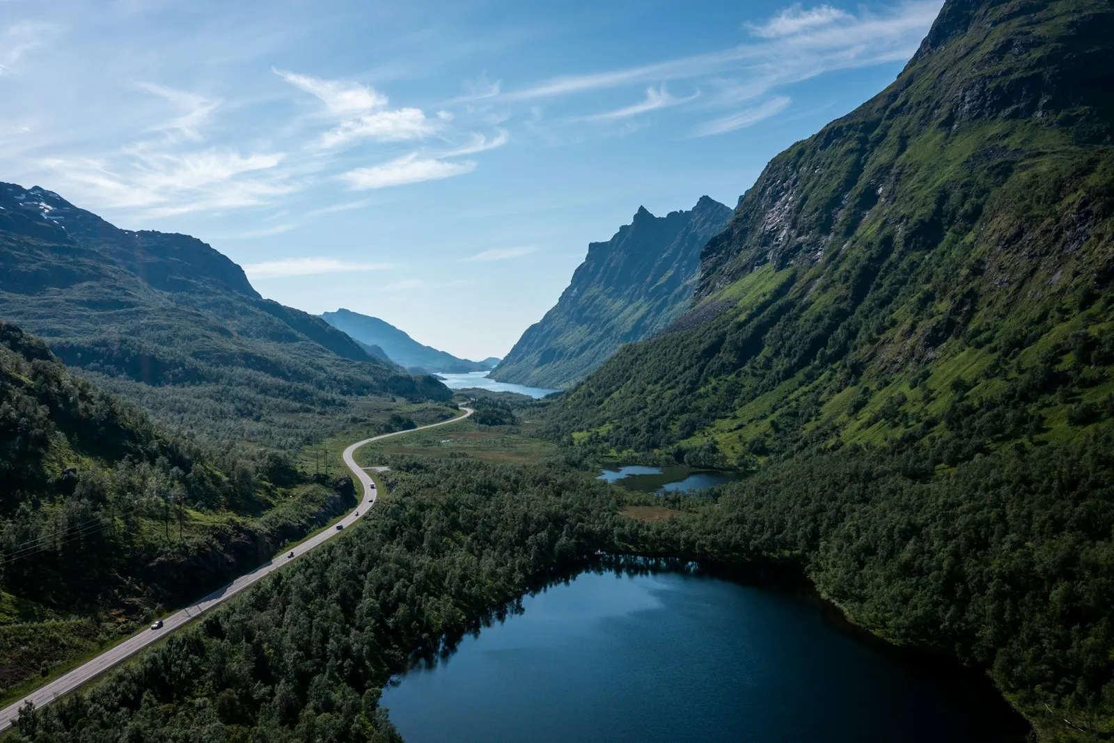 Green mountains beside a river under a blue sky in daytime