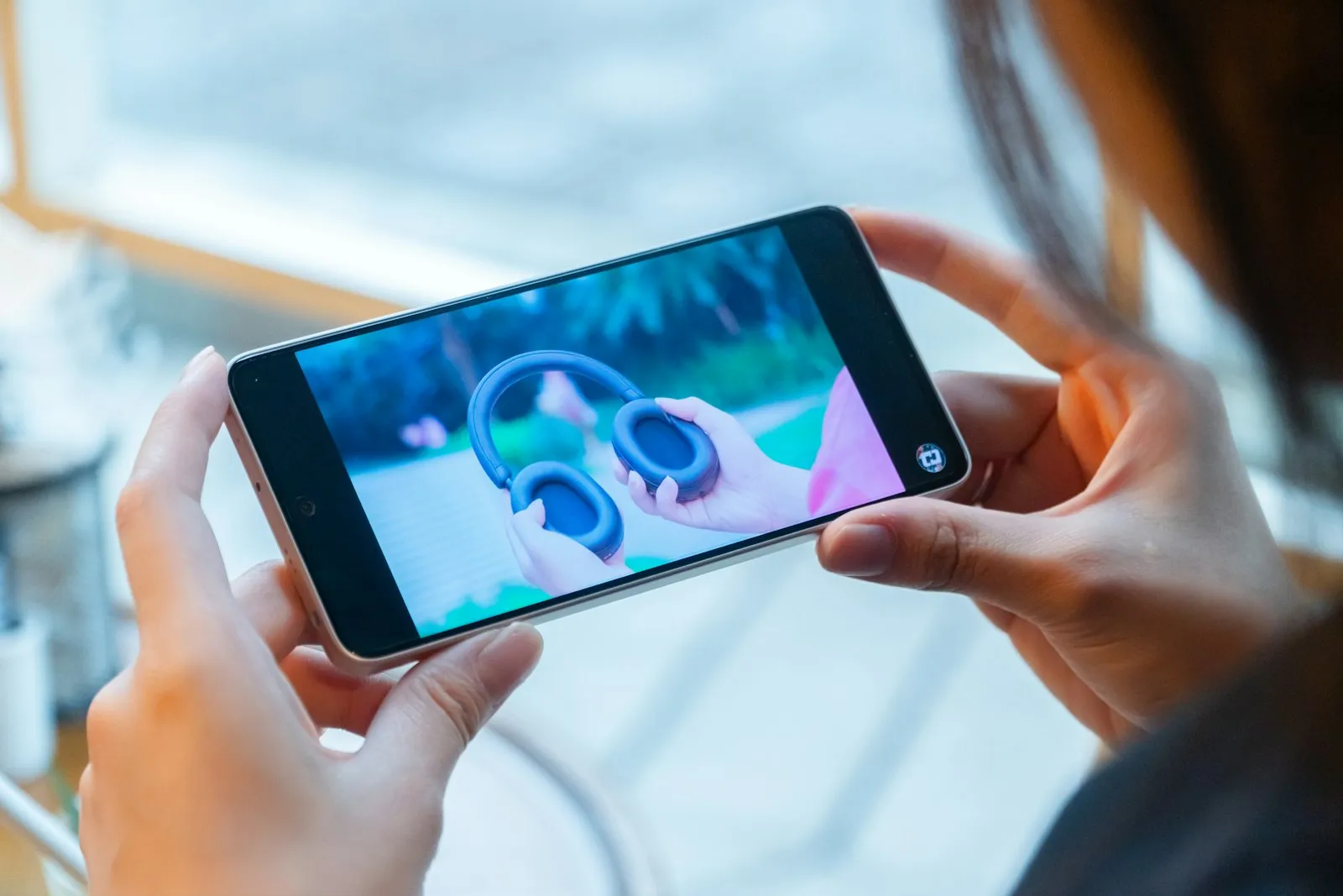 A woman holding a smartphone with a video on its screen