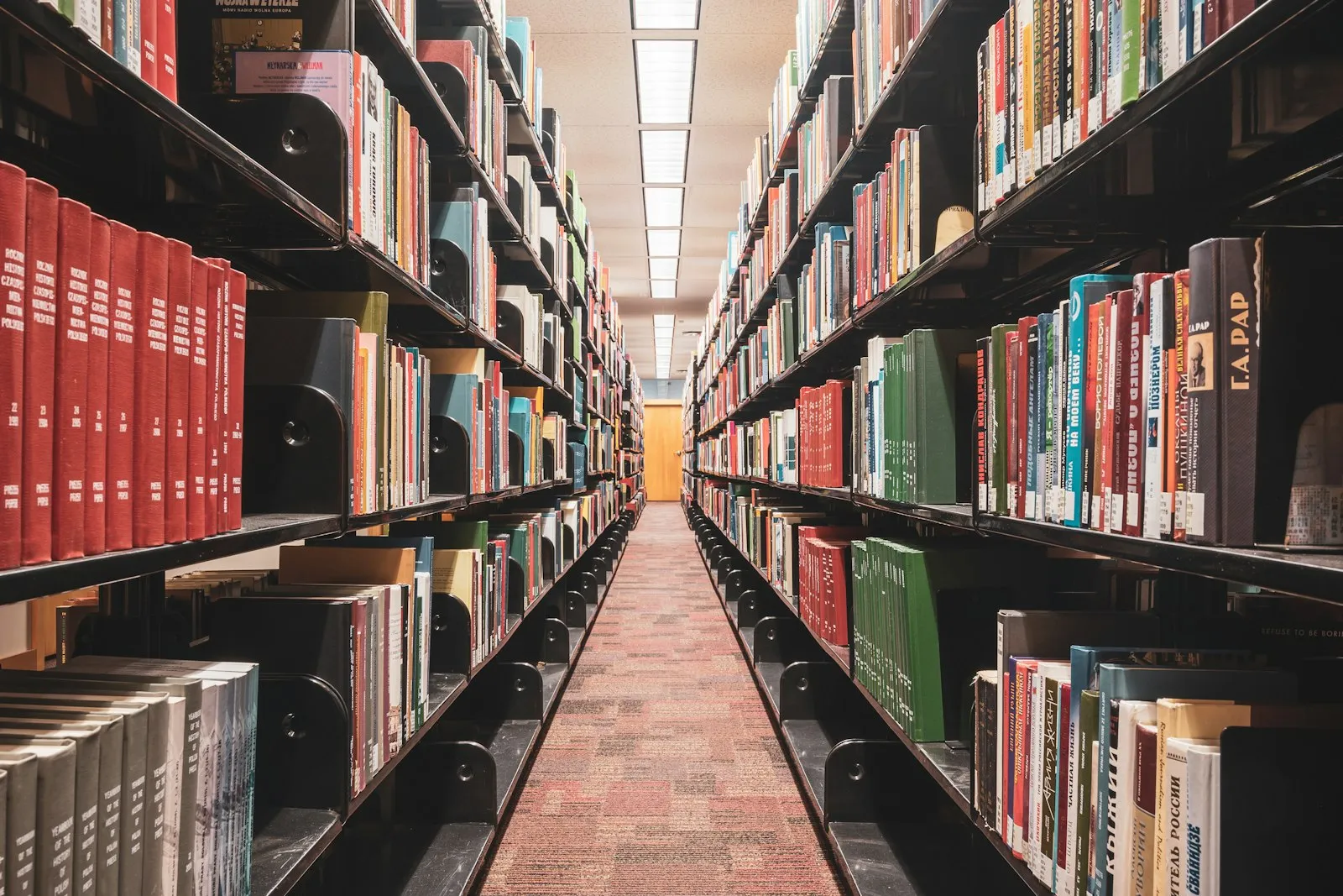 Long aisle between tall library shelves full of books